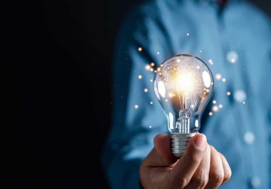 Innovation through ideas and inspiration ideas. Human hand holding light bulb to illuminate, idea of creativity and inspiration concept of sustainable business development.