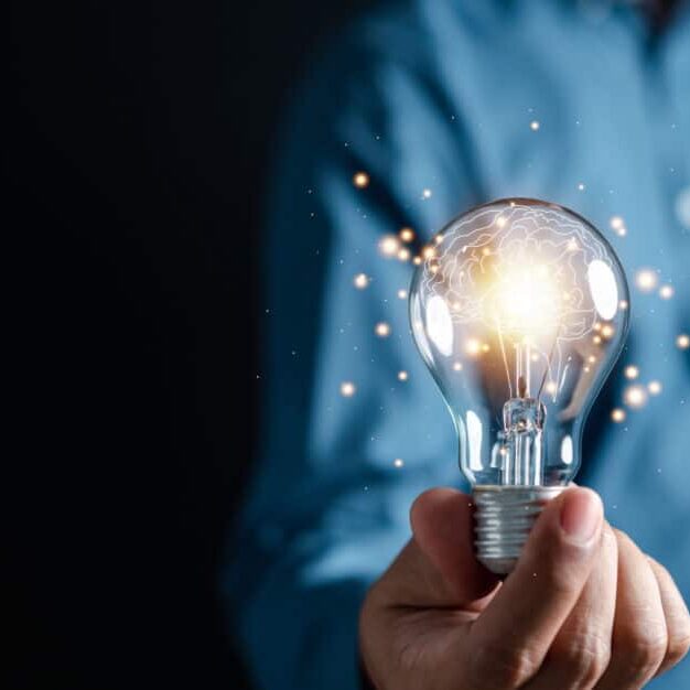 Innovation through ideas and inspiration ideas. Human hand holding light bulb to illuminate, idea of creativity and inspiration concept of sustainable business development.